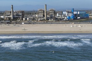 Huntington Beach, CA - April 5: An aerial view of the AES Huntington Beach Energy Center, the proposed site of the Poseidon Desalination Plant, which would draw ocean water through an existing intake pipe. In the background is neighboring residential community, Edison Community Park, Edison High School, ASCON toxic State superfund cleanup site, the proposed Magnolia Tank Farm Lodge, restaurants, and retail, upper right, the Huntington Beach Wetlands, middle right, and Huntington State Beach. Photo taken Tuesday, April 5, 2022. The partially retired Huntington Beach Generating Station consists of four generating units but only unit 2 is still in commercial operation as a legacy unit and has an extension to operate through the end of 2023, issued by the California State Water Boards. Unit 2 runs to support peak demands and has a net output capacity of 225 megawatts. The 644 MW combined cycle gas turbine generator, shown in blue and white, began operation on June 25, 2020. Environmental groups have fought Poseidon, arguing that it is privatizing a public resource, has failed to adapt an old proposal to new state ocean protections from killing sea life and that the company is trying to fill a need that doesn't exist, uses too much natural gas energy. Environmental justice activists say water rates could be raised as much as $6 per month. Supporters say ocean desalination as an inexhaustible, local supply for a region that imports much of its water from increasingly unreliable, distant sources. Another stumbling block for Poseidon is state requirements to mitigate the project's harm to the marine environment. Poseidon would draw 106 million gallons a day of seawater through the huge offshore intake pipe, which would be screened, and use reverse osmosis membranes to rid the seawater of salt and impurities. That process would produce 56 million gallons a day of brine concentrate - roughly twice as salty as the ocean - which would be dumped back into the Pacific via a 1,500-foot discharge pipe equipped with outfall diffusers to promote mixing and dilution. The intake and discharge operations will take a toll on plankton, which plays a crucial role in the marine food chain, killing an estimated 300,000 microscopic organisms a day. (Allen J. Schaben / Los Angeles Times)